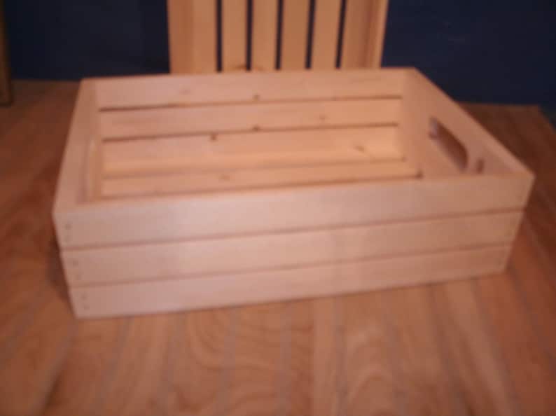 Peut inclure: Une caisse en bois naturel avec une poign&eacute;e sur le c&ocirc;t&eacute;. La caisse est en bois brut et a une forme rectangulaire.