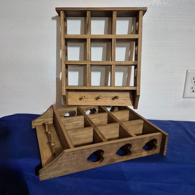 May include: Two wooden shelves with heart-shaped cutouts. The top shelf has 12 square compartments and a small drawer. The bottom shelf has 12 square compartments and a row of heart-shaped cutouts.