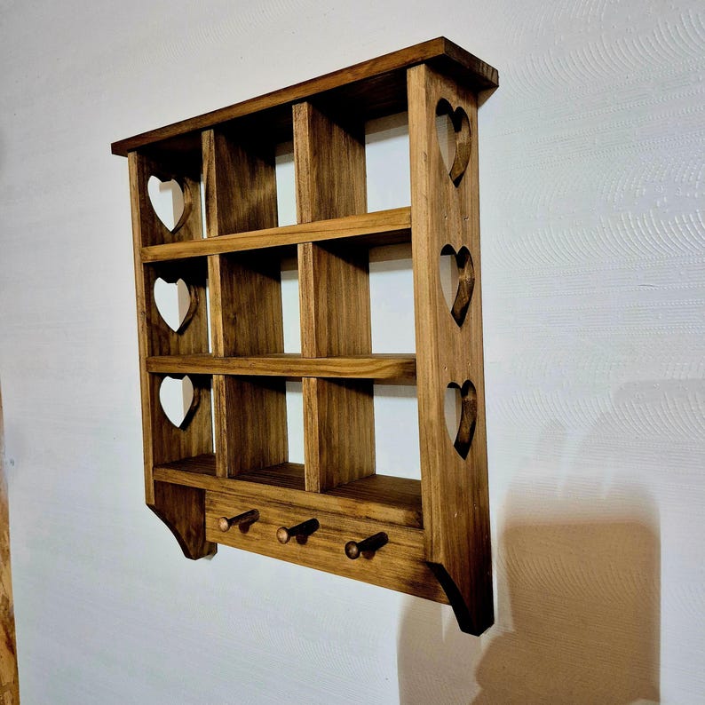 May include: A wooden wall shelf with a heart-shaped cutout design. The shelf has multiple compartments and is stained a dark brown color.