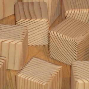 May include: A group of wooden blocks with a natural wood finish. The blocks are arranged in a random pattern and have a smooth, polished surface.