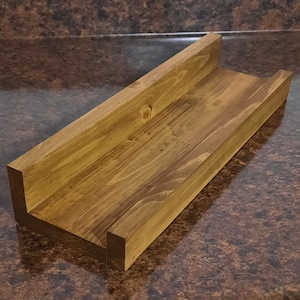 May include: A wooden shelf with a U-shaped front edge. The shelf is stained a dark brown color and has a natural wood grain pattern.