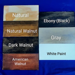 Puede incluir: Cinco muestras de madera que muestran diferentes manchas de madera: Natural, Nogal natural, Nogal oscuro, Nogal americano, &Eacute;bano (negro), Gris y Pintura blanca.