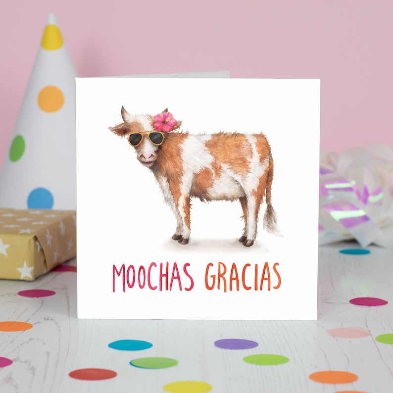 Puede incluir: Una tarjeta blanca con una vaca marr&oacute;n y blanca que lleva gafas de sol y una flor rosa. El texto "MOOCHAS GRACIAS" est&aacute; escrito en rojo en la tarjeta.