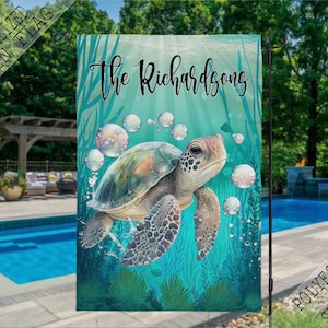 May include: A personalized garden flag with a sea turtle swimming through a turquoise blue ocean with bubbles. The flag reads "The Richardsons" in black text.