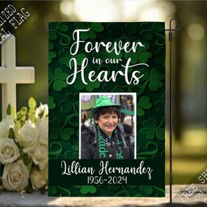 May include: A green memorial flag with a shamrock pattern and the text "Forever in our Hearts". A photo of a woman with a green hat is in the center of the flag. The text "Lillian Hernandez 1956-2024" is at the bottom of the flag.