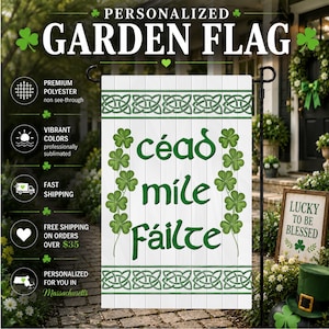 May include: A white garden flag featuring a green Celtic knot border at the top and bottom. The center displays the green text "céad mile Fáilte" flanked by two vertical columns of green shamrocks. The flag is mounted on a black metal stand.