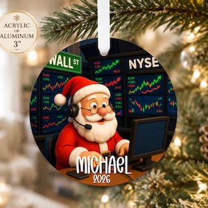 May include: A round 3-inch acrylic or aluminum ornament featuring a cartoon Santa Claus wearing a headset and glasses, sitting at a desk with computer monitors displaying stock market charts, a Wall St sign, the name MICHAEL, and the year 2026.