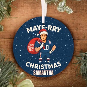 May include: Round Christmas ornament with a blue background and white text that reads "MAYERRY CHRISTMAS SAMANTHA". The ornament features a football player wearing a Santa hat and holding a sack.
