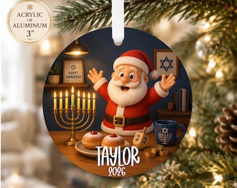 Può includere: Un ornamento rotondo di 7,6 cm in acrilico o alluminio con un Babbo Natale in stile cartoon, una menorah dorata con candele accese, due ciambelle, un dreidel e una tazza blu. Il testo Taylor 2026 è stampato nella parte inferiore.