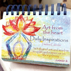 May include: A colorful calendar with a watercolor painting of a person holding a lotus flower. The text on the cover reads "Art from the heart Daily Inspirations Timeless Calendar 365 days of art and wisdom to uplift and inspire us on life's journey annie b."