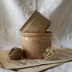 以下が含まれることがあります： 黒い持ち手と「But First, Coffee」の文字が黒い手書き風フォントで書かれた白いセラミックマグ。マグカップは白い表面に置かれています。