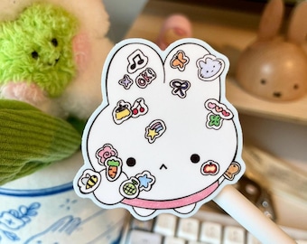 May include: White bunny sticker with various colorful illustrations, including musical notes, cherries, and a cloud. The sticker has a pink outline and the word "OK!" is visible. The sticker is on a white pen.