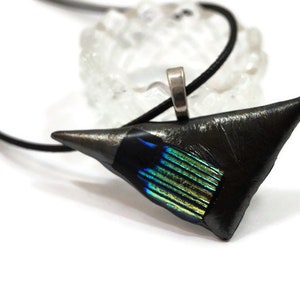 May include: A black pendant necklace with a triangular, textured pendant. The pendant has a silver bail and a section of iridescent blue and green glass. The necklace cord is black.