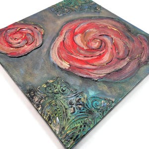 May include: Square canvas art featuring two raised red rose designs with gold accents. The background is a textured teal and gray with ornate green corner details. A unique piece of floral wall decor.