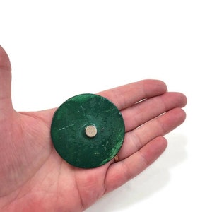 K&ouml;nnte beinhalten: Eine runde, gr&uuml;ne Scheibe mit einem kleinen, silbernen Magneten in der Mitte.