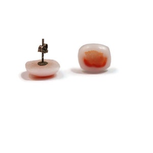 May include: A pair of white and orange square shaped earrings with a silver post.