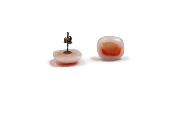 May include: A pair of white and orange square shaped earrings with a silver post.