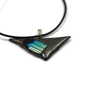 May include: A triangular pendant necklace with a black cord. The pendant is a dark gray color with a section of iridescent blue and green glass. The pendant is approximately 1.5 inches wide.