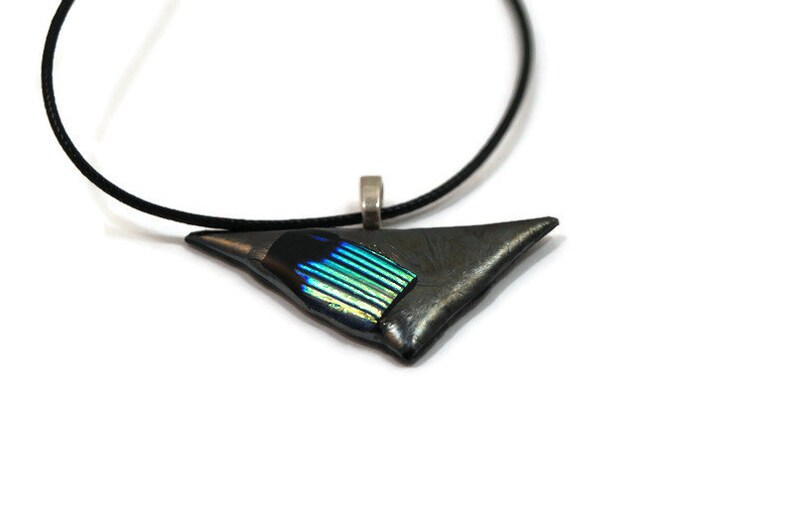May include: A triangular pendant necklace with a black cord. The pendant is a dark gray color with a section of iridescent blue and green glass. The pendant is approximately 1.5 inches wide.