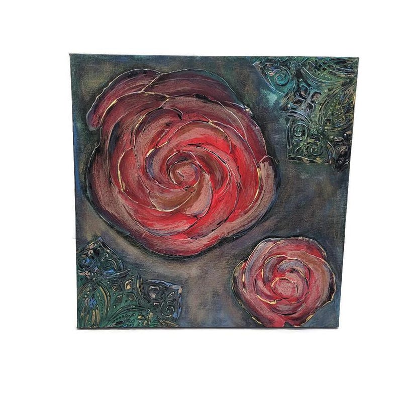 May include: Square canvas art featuring two large red roses with gold accents and a smaller rose. The background is a dark gray with green decorative elements in the corners. The roses have a textured, painted appearance.