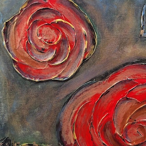 May include: Close-up of a textured canvas painting featuring two large, stylized red roses with gold accents. The roses have a three-dimensional effect, with dark brown and gold outlines. The background is a blend of dark gray and brown.