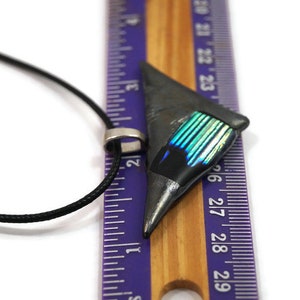May include: A geometric pendant necklace with a black cord. The pendant is a dark gray triangle with a section of iridescent blue and green. The pendant is approximately 1 inch long.