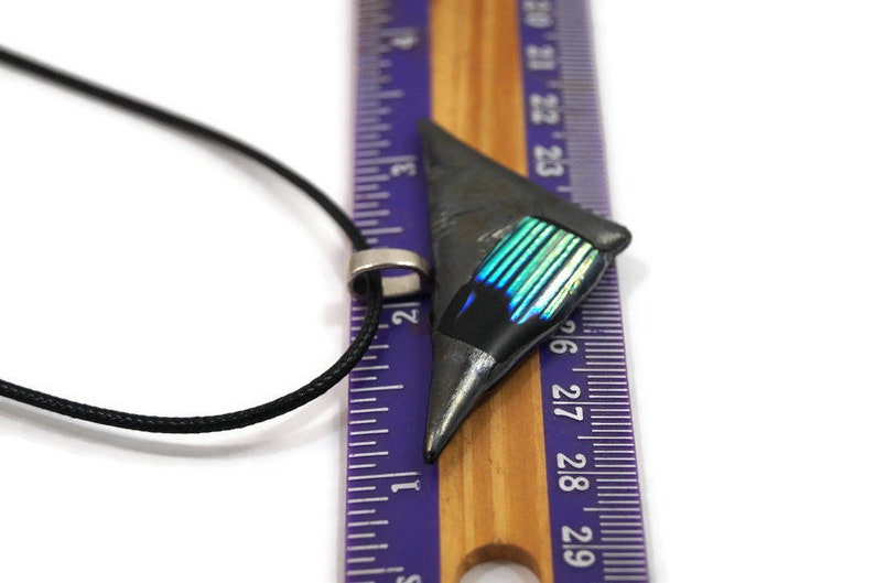 May include: A geometric pendant necklace with a black cord. The pendant is a dark gray triangle with a section of iridescent blue and green. The pendant is approximately 1 inch long.