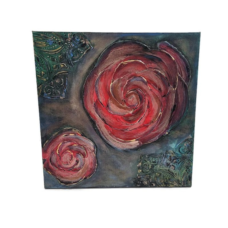 May include: Square canvas art featuring two red roses with textured brushstrokes. The roses are set against a dark gray background with decorative green and blue corner accents. The artwork has a handmade appearance.