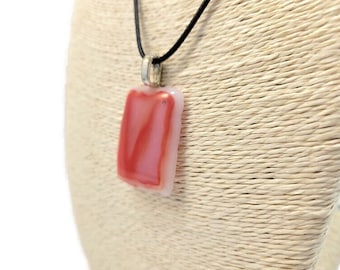 May include: A red and white glass pendant necklace with a black cord. The pendant is rectangular and has a swirl pattern.
