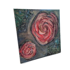 May include: Square canvas art featuring two large red roses and a smaller one, painted with textured brushstrokes. The background is a dark gray with green and gold decorative elements in the corners. The artwork has a three-dimensional effect.