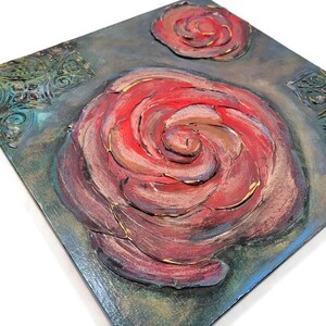 May include: Square canvas art featuring a large, textured red rose with a smaller rose above it. The artwork has a dark, textured background with hints of teal and gold accents. The rose petals have gold highlights.