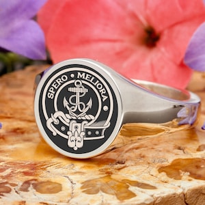 May include: A silver signet ring with a black enamel crest featuring an anchor and the text "SPERO MELIORA".