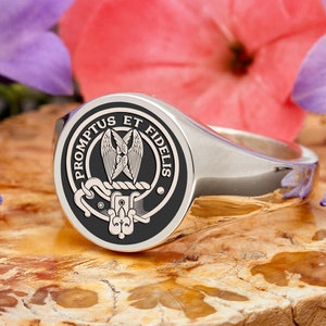 May include: A silver signet ring with a black enamel crest featuring a winged heart and the text "PROMPTUS ET FIDELIS".