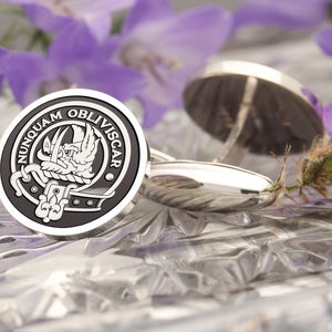May include: Silver cufflinks with a black and white enamel design featuring a crest with the text "NUNQUAM OBLIVISCAR".