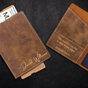 Puede incluir: Dos porta pasaportes de cuero marr&oacute;n con grabados personalizados. Un porta pasaportes tiene el nombre "David Williams" y el otro la cita "El mundo es demasiado grande para quedarse en un solo lugar. Te quiero, Angela."