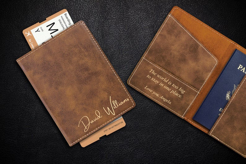 Puede incluir: Dos porta pasaportes de cuero marr&oacute;n con grabados personalizados. Un porta pasaportes tiene el nombre "David Williams" y el otro la cita "El mundo es demasiado grande para quedarse en un solo lugar. Te quiero, Angela."
