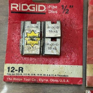May include: RIDGID 1/2" pipe dies on a red and white card. The card reads "12-R" and "High Speed". The Ridge Tool Co. is printed on the card. The dies are for threading pipes.