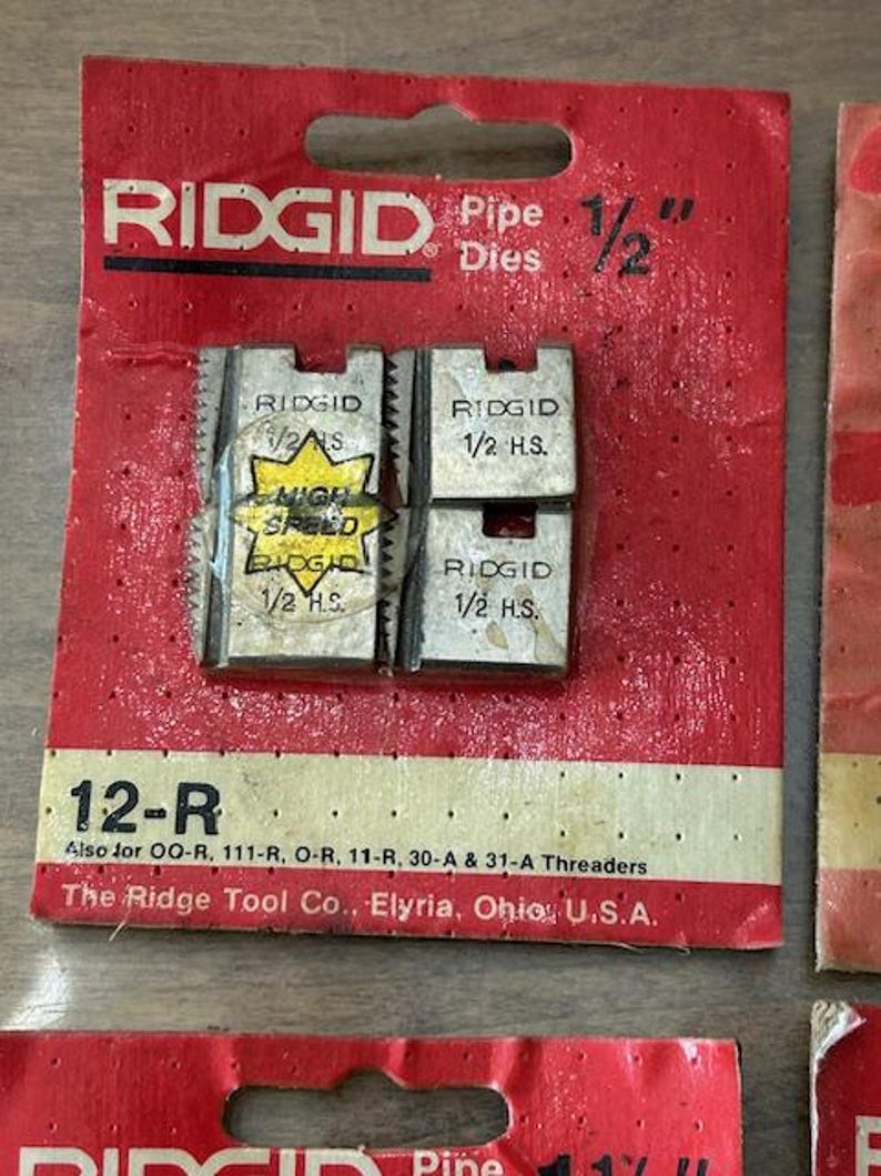 May include: RIDGID 1/2" pipe dies on a red and white card. The card reads "12-R" and "High Speed". The Ridge Tool Co. is printed on the card. The dies are for threading pipes.