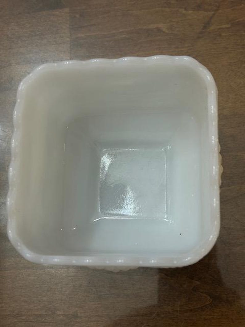 May include: A square white milk glass bowl featuring a scalloped rim with a beaded texture along the top edge. The interior is smooth and glossy, while the exterior walls display a repeating embossed pattern of small raised dots.