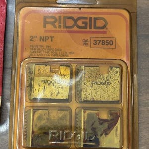 May include: A package of RIDGID 2" NPT pipe dies. The package is a clear plastic with a gold-colored cardboard backing. The dies are gold-colored and are labeled with the RIDGID brand name and the catalog number 37850.