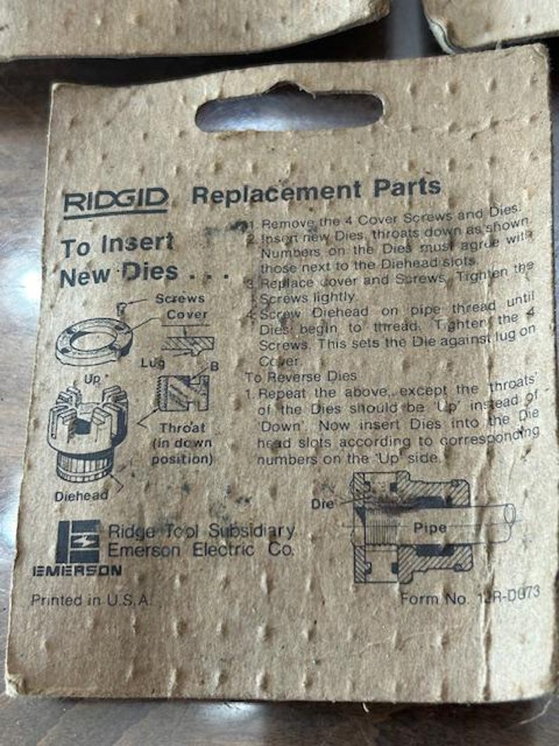 May include: Cardboard packaging for RIDGID replacement parts. The packaging includes instructions for inserting new dies, diagrams, and the Ridge Tool Subsidiary Emerson Electric Co. logo. The text "Printed in U.S.A." is visible.