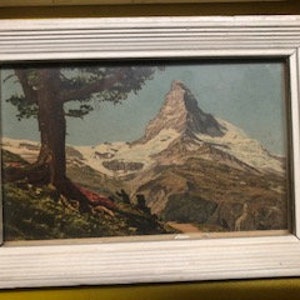 Peut inclure: Une estampe vintage encadr&eacute;e repr&eacute;sentant un paysage de montagne avec un sommet enneig&eacute; et un arbre au premier plan.