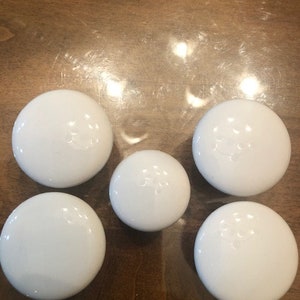 May include: Six white round ceramic knobs with a raised design.
