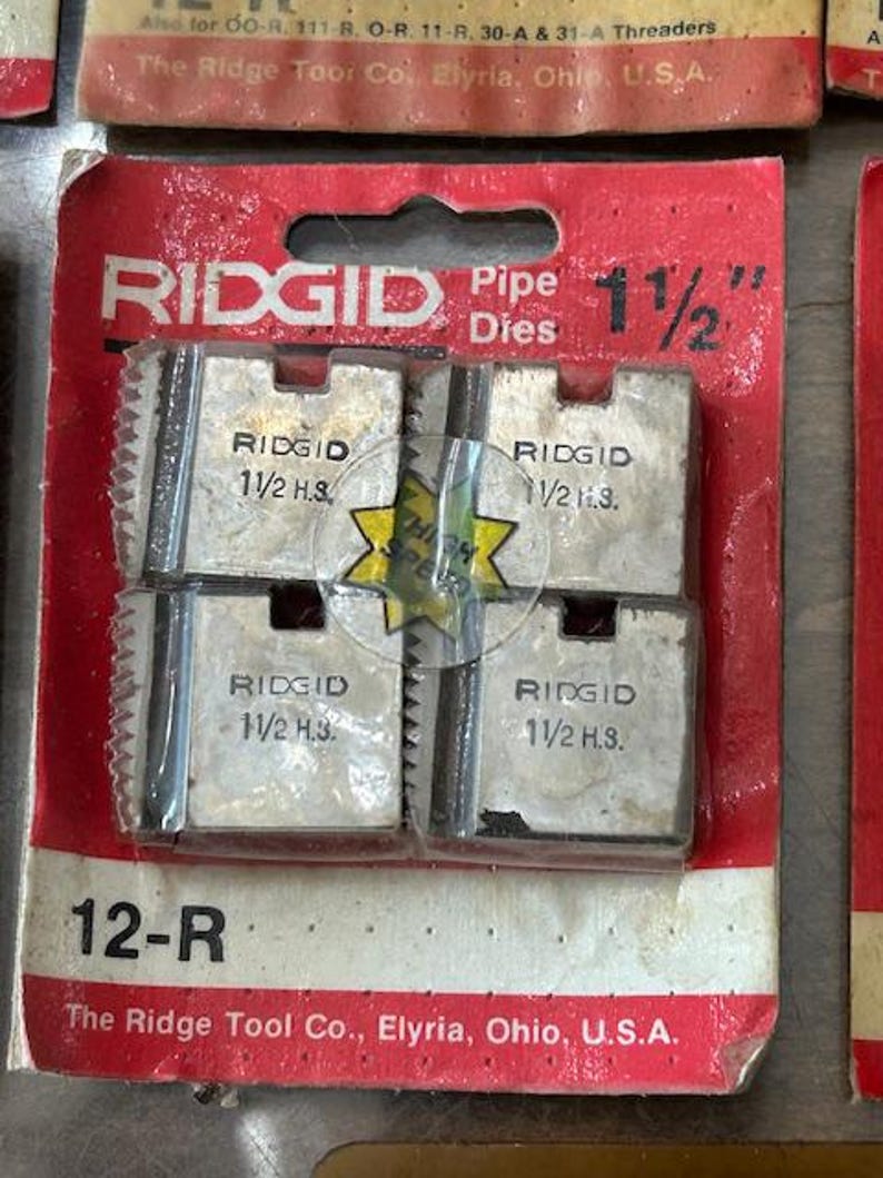 May include: RIDGID pipe dies, 1 1/2 inch, in a red and white package. The package includes four metal dies with the RIDGID logo and size information. The package also includes the text "12-R" and "The Ridge Tool Co., Elyria, Ohio, U.S.A."