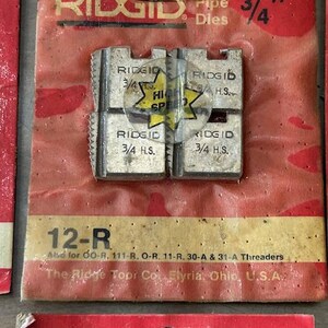 May include: Close-up of a package of RIDGID pipe dies. The package is red and has the text "RIDGID Pipe Dies 3/4"" printed on it. The dies are silver and marked "3/4 H.S." and "High Speed".