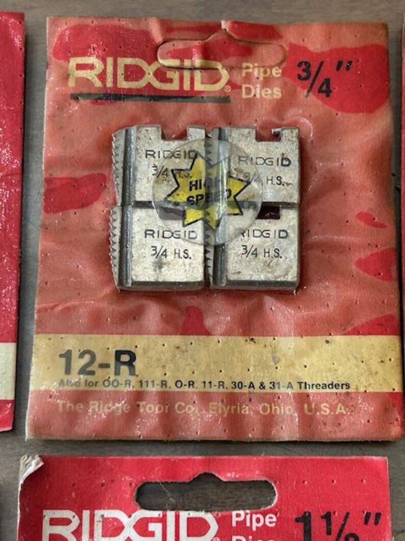 May include: Close-up of a package of RIDGID pipe dies. The package is red and has the text "RIDGID Pipe Dies 3/4"" printed on it. The dies are silver and marked "3/4 H.S." and "High Speed".