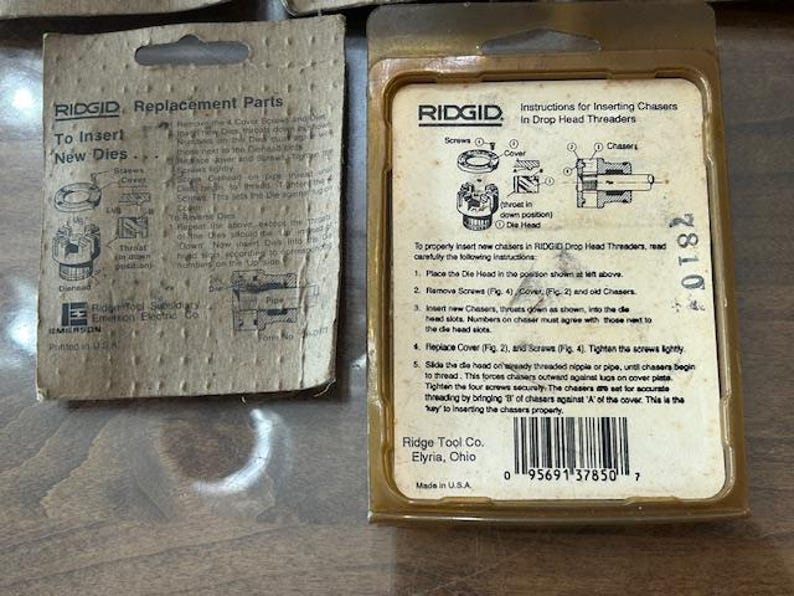 May include: Two vintage RIDGID replacement parts packages. One package is a tan cardboard with instructions for inserting new dies. The other is a clear plastic package with instructions for inserting chasers in drop head threaders.
