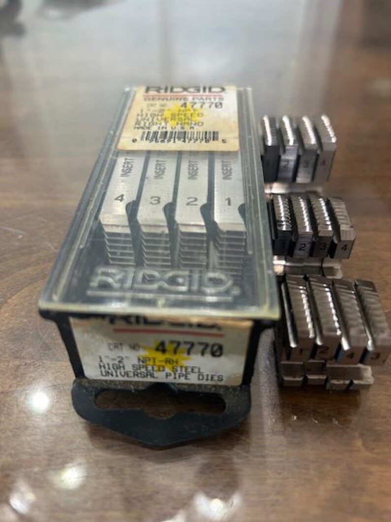May include: A set of RIDGID high-speed steel universal pipe dies, model 47770, with inserts numbered 1 through 4. The dies are in a clear plastic case with the RIDGID logo and product information.