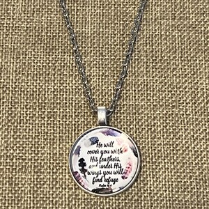 Puede incluir: Un collar de cadena de plata con un colgante redondo que presenta un dise&ntilde;o floral de estilo acuarela y el texto "He will cover you with His feathers, and under His wings you will find refuge. Psalm 91:4".