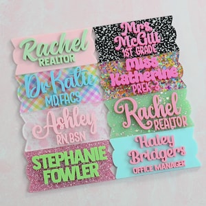 May include: A collection of eight rectangular acrylic name badges with scalloped edges, featuring various patterns including black and white composition, colorful confetti, and glitter. Each badge displays raised 3D lettering with names and titles.
